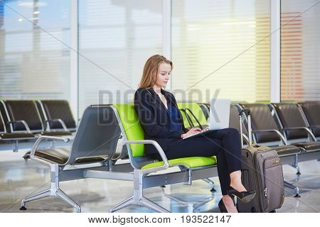 Woman In International Airport Terminal, Working On Her Laptop