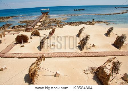 Tilted palm-leaf umbrellas on Constantia sandy beach in Famagusta Cyprus. Photo taken in March 2009