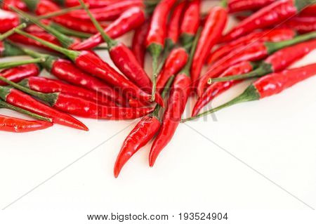 red hot chili peppers, popular spices concept - beautiful handful of red hot pepper in bulk, fresh ripe pods with green peduncle scattered on white background, flat lay, free space for the text.
