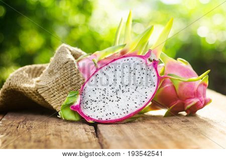 dragon fruit slice on wood table and green nature background with sunlight