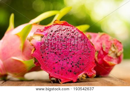 dragon fruit slice on wood table and green nature background with sunlight
