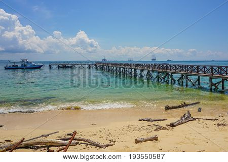Wooden jetty over the beautiful Rusukan Besar island tropical beach with blue sky and clouds in Labuan Pearl of Borneo,Sabah.