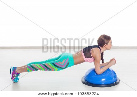 Young athletic woman doing exercise on bosu. Training yoga pilates. gym