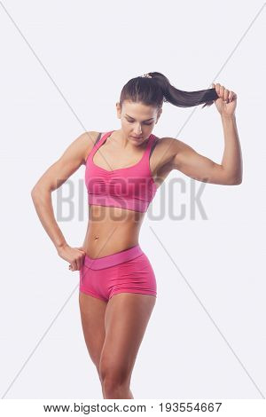 Young beautiful sporty woman with long hair in pink lingerie white background. Smiles
