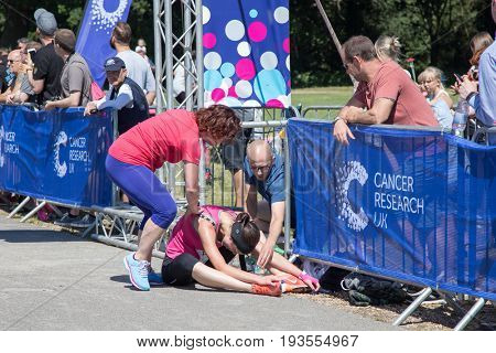 Southampton, Uk - 2 July 2017: Athlete, suffering from heat exhaustion, is help by bystanders at the finish line of Race for Life. This annual race is run by women to raise money for Cancer Research.