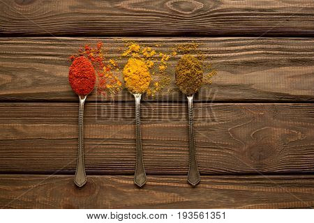 Spice. Spice powder on a wooden background. Three spoons with various spices.