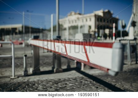 White and red access barrier in horizontal position in a car park entrance.