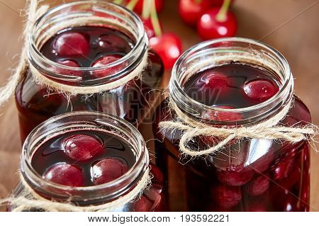 Cherry jam on wooden background in glass jars
