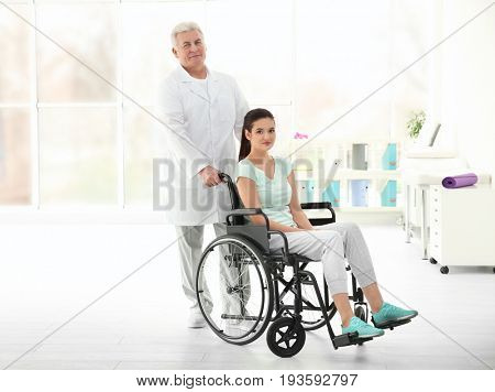 Young disabled woman with senior orthopedist in rehabilitation clinic