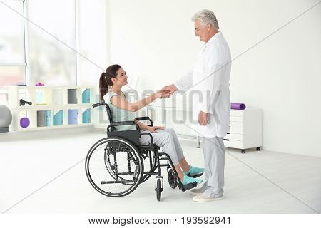 Young disabled woman with senior orthopedist in rehabilitation clinic