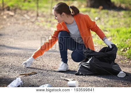 Young beautiful volunteer picking up litter in park