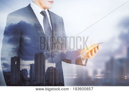Businessman using mobile phone on blurry city background with copy space. Social media concept. Double exposure