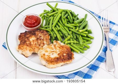 Lunch from green beans and cutlets on white wooden table. Studio Photo