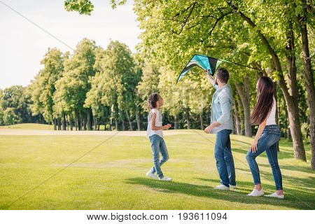 Father Helping Daughter Launching Kite While Spending Time Together In Park