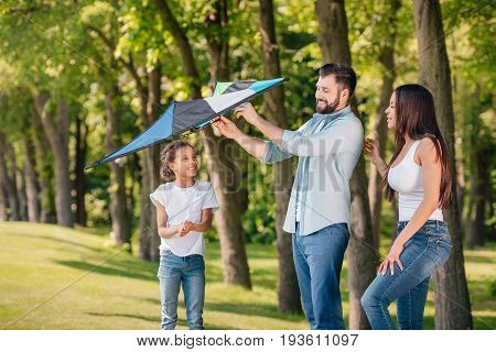 Father Helping Daughter To Launch A Kite While Spending Time Together In Park