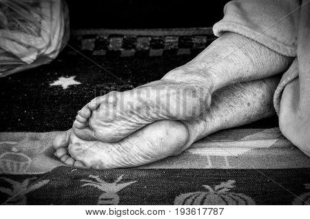 Bare feet of homeless person sleeping on the street. Black and white. Homelessness. Social. Documentary. Street.