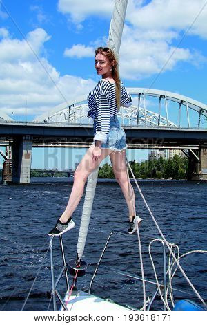 sexy adorable woman in shorts and striped sailor T-shirt. Fashionable young beautiful girl posing on a yacht. Sunny day. Summer style. Coast