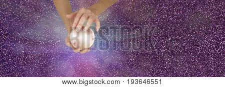 Fortune Teller holding crystal ball on sparkling banner - Female fortune teller holding a large  crystal ball in cupped hands against a sparkling magenta  background with copy space