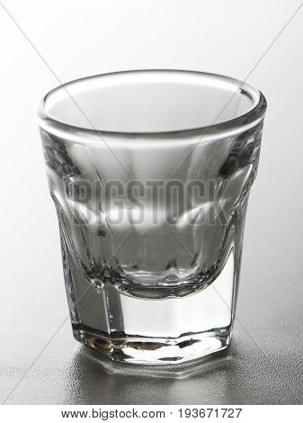 Shot glass for alcoholic drink as tequila or vodka or gin on grey gradient background