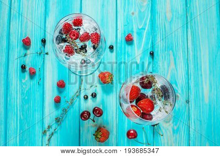 Refreshing cocktail with vodka martini with ice and berries on wood table. Top view