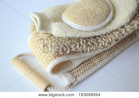 Top close up view of a set of body massage brushes for dry brushing with a red rose on white