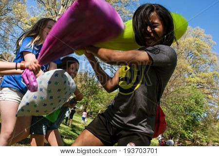ATLANTA, GA - APRIL 2017:  A young adult woman fends off the pillow attacks of several girls as they participate in the annual International Pillow Fight Day in Grant Park in Atlanta GA on April 1 2017.