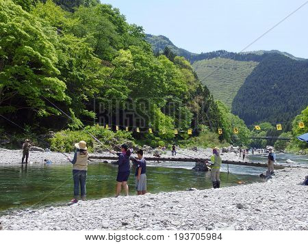2016 May 5. TAMAKAWA TOKYO JAPAN. People are fishing at TAMAKAWA river that surrounded by green forest and natural MITAKE mountain