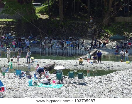 2016 May 5. TAMAKAWA TOKYO JAPAN. People are fishing at TAMAKAWA river that surrounded by green forest and natural MITAKE mountain.