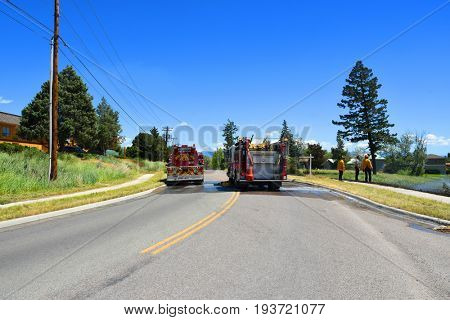 KALISPELL, MONTANA, USA - June 21, 2017: Fire crew observe grass fire scene as a water truck leaves the scene
