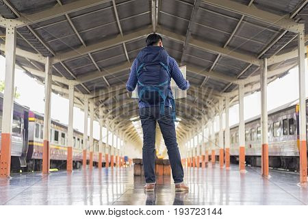 man traveler with backpacker look searching location at trainstation travel concept
