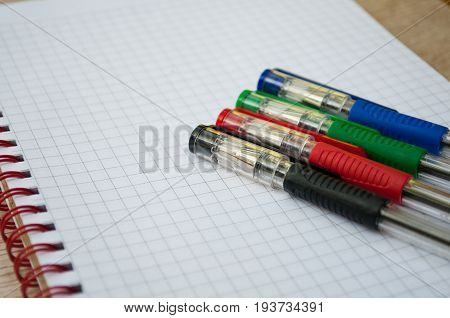 black, blue, red, green pen lying on the notebook
