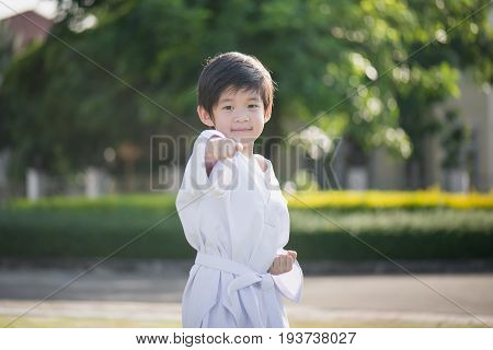 Cute Asian child in white kimono during training karate in summer outdoors