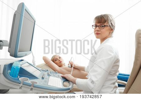 Young woman getting ultrasound scanning examination on her breast at the clinic.