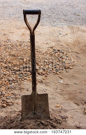 Old rusty shovel stab above the sand.