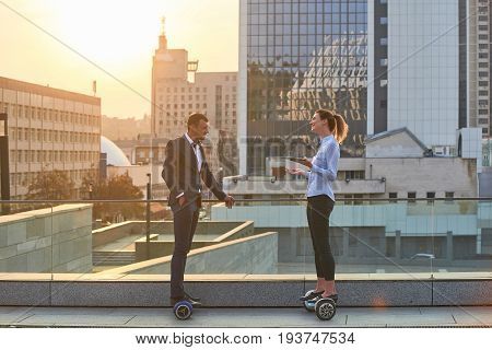 Businessman and woman, city background. People on hoverboards. Shape the future of business.