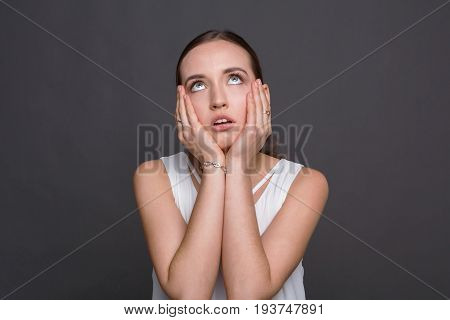 Bored girl rolling her eyes and touch cheeks. Tired young woman demonstrates her fatigue, monotony concept