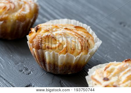 Sweet tasty mufins with sugar powder close up on wooden background, amcro