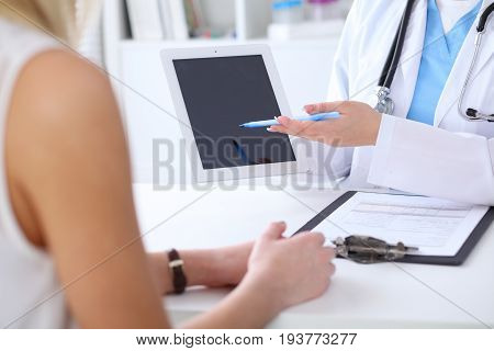 Close up of a doctor and  patient hands while phisician pointing into tablet computer monitor. Medicine and health care concept