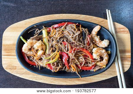 Wok spaghetti with red and green peppers and shrimps. Restaurant food. Served with chinese chopsticks