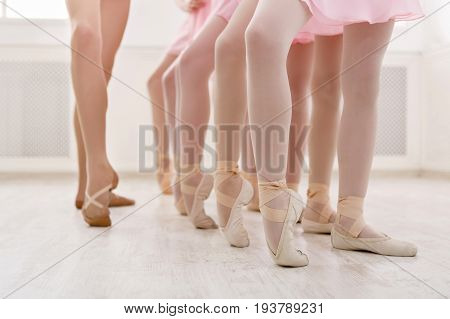 Ballet background, young ballerinas training. Little dancers legs in pointe shoes, making exercises. Classical dance school, copy space