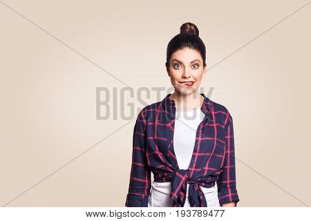 Portrait of beautiful happy funny girl in casual style looking at camera with big eyes and biting lips. studio shot on beige background.