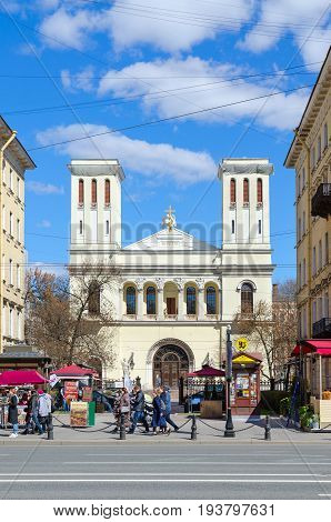 SAINT PETERSBURG RUSSIA - MAY 3 2017: Unknown people are walking along Nevsky Prospect near Lutheran Church of Saints Peter and Paul (Petrikirche) St. Petersburg Russia