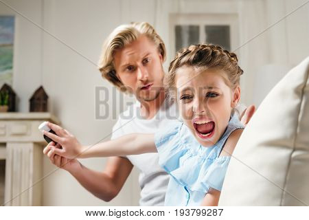 Father trying to give medicine to screaming angry child at home
