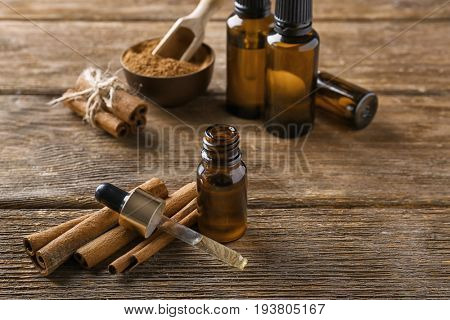 Composition with bottle of cinnamon oil on wooden background