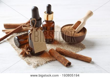Composition with bottles of cinnamon oil on wooden background