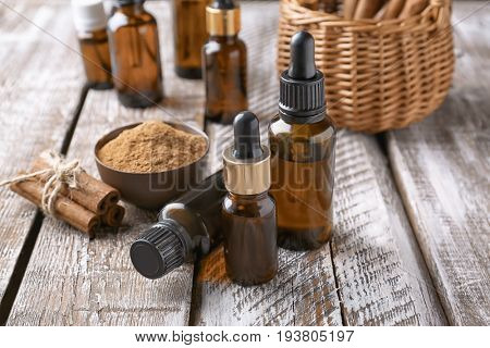 Composition with bottles of cinnamon oil on wooden background