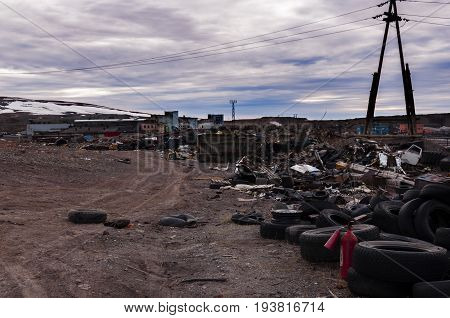 Dirt road in the middle of a garbage dump old car tires against a stormy sky