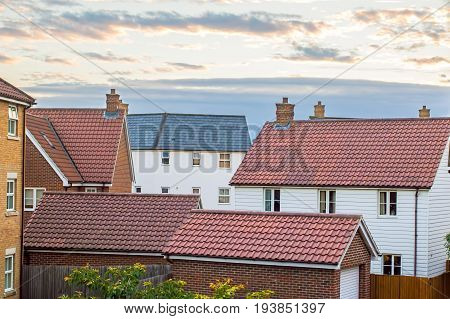 Modern housing estate UK. Variety of homes and garage buildings against cloudscape sky.