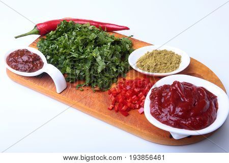 Fresh green cilantro, coriander leaves, tomato paste, chili pepper and spices on a wooden board. Ingredients for meat sauce