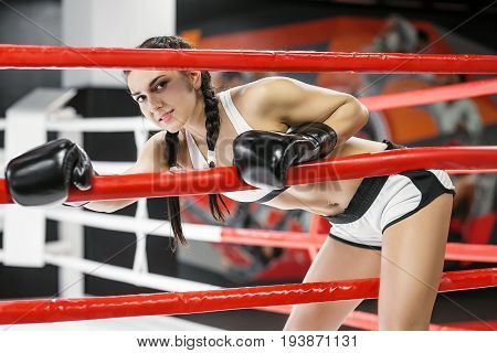 A woman climbs over the ropes of a boxing ring